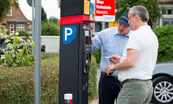 DB Bahnpark Mitarbeiter unterstützt Kunden am Parkscheinautomat