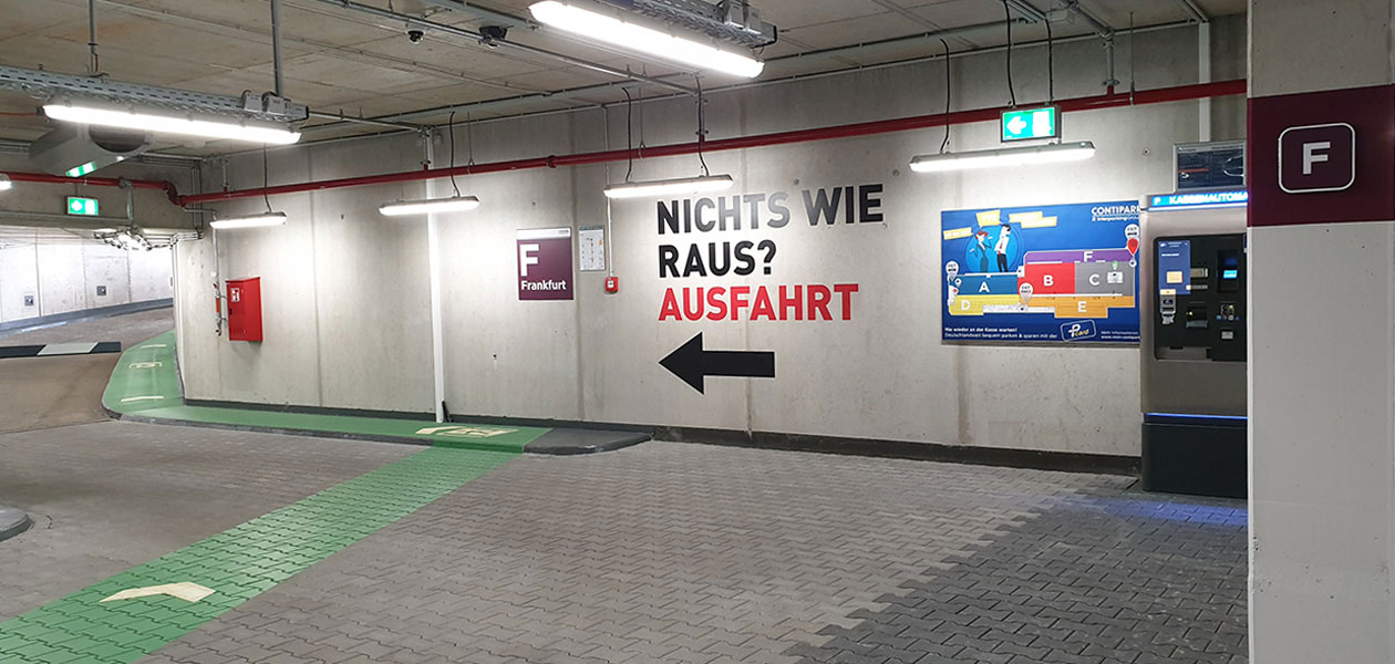 Schriftzug „Nichts wie raus? Ausfahrt“ mit Pfeil in Richtung Ausfahrt an der Parkhauswand