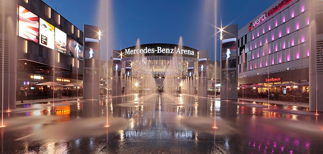 Blick über den beleuchteten Vorplatz zur Mercedes Benz Arena in Berlin in der Dämmerung